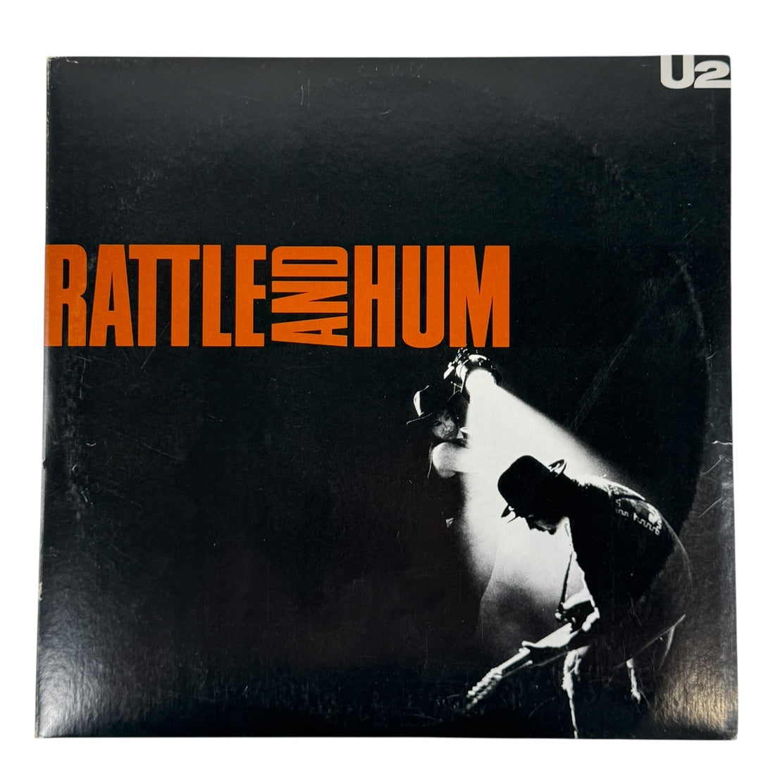Album cover of 'Rattle and Hum' by U2 with a black background and orange text.