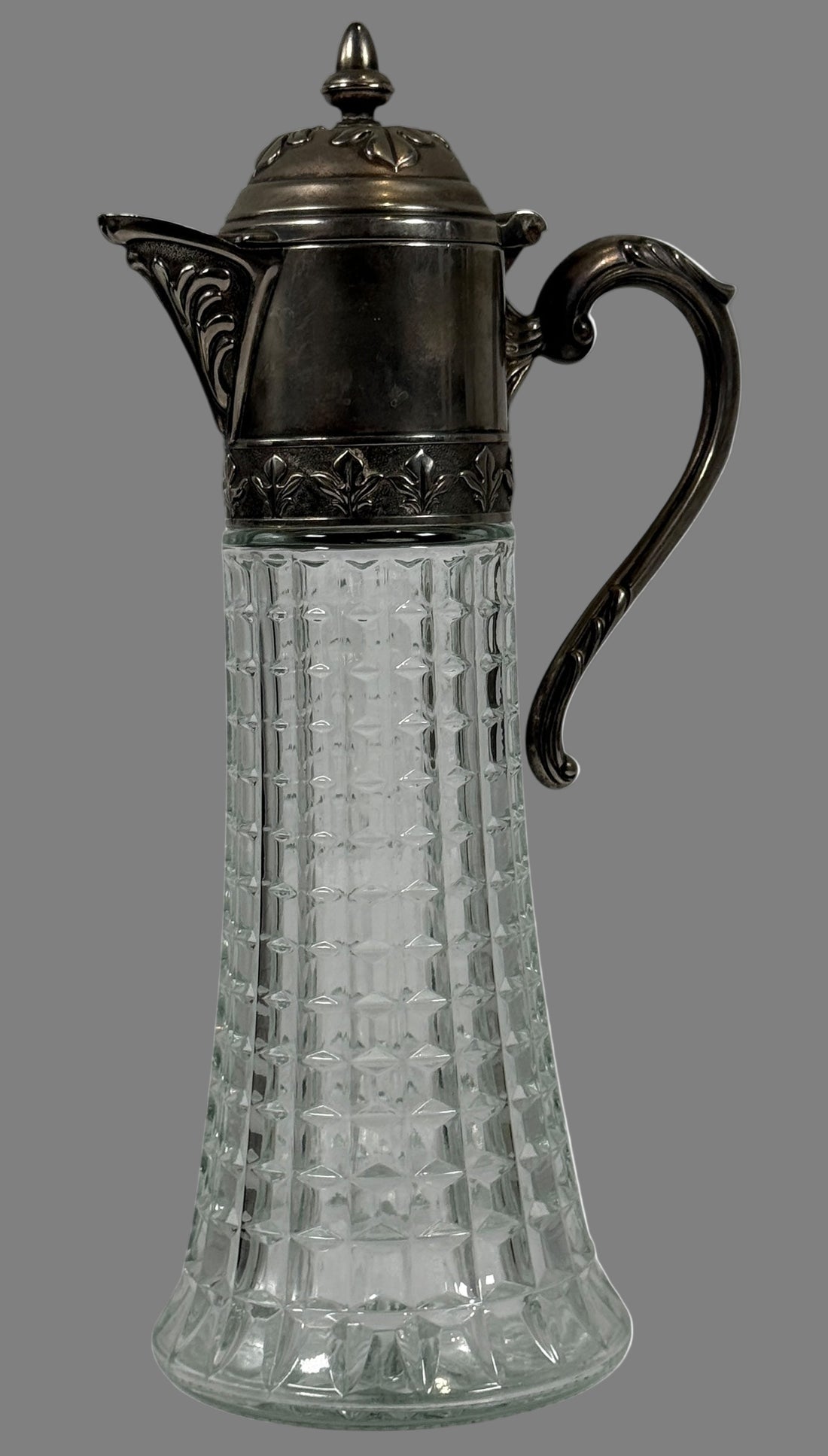 Decorative glass carafe with metal lid and handle on a white background