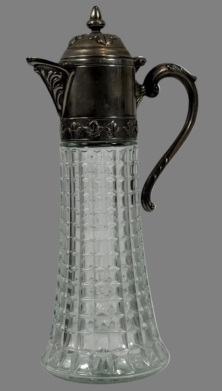 Decorative glass carafe with metal lid and handle on a white background