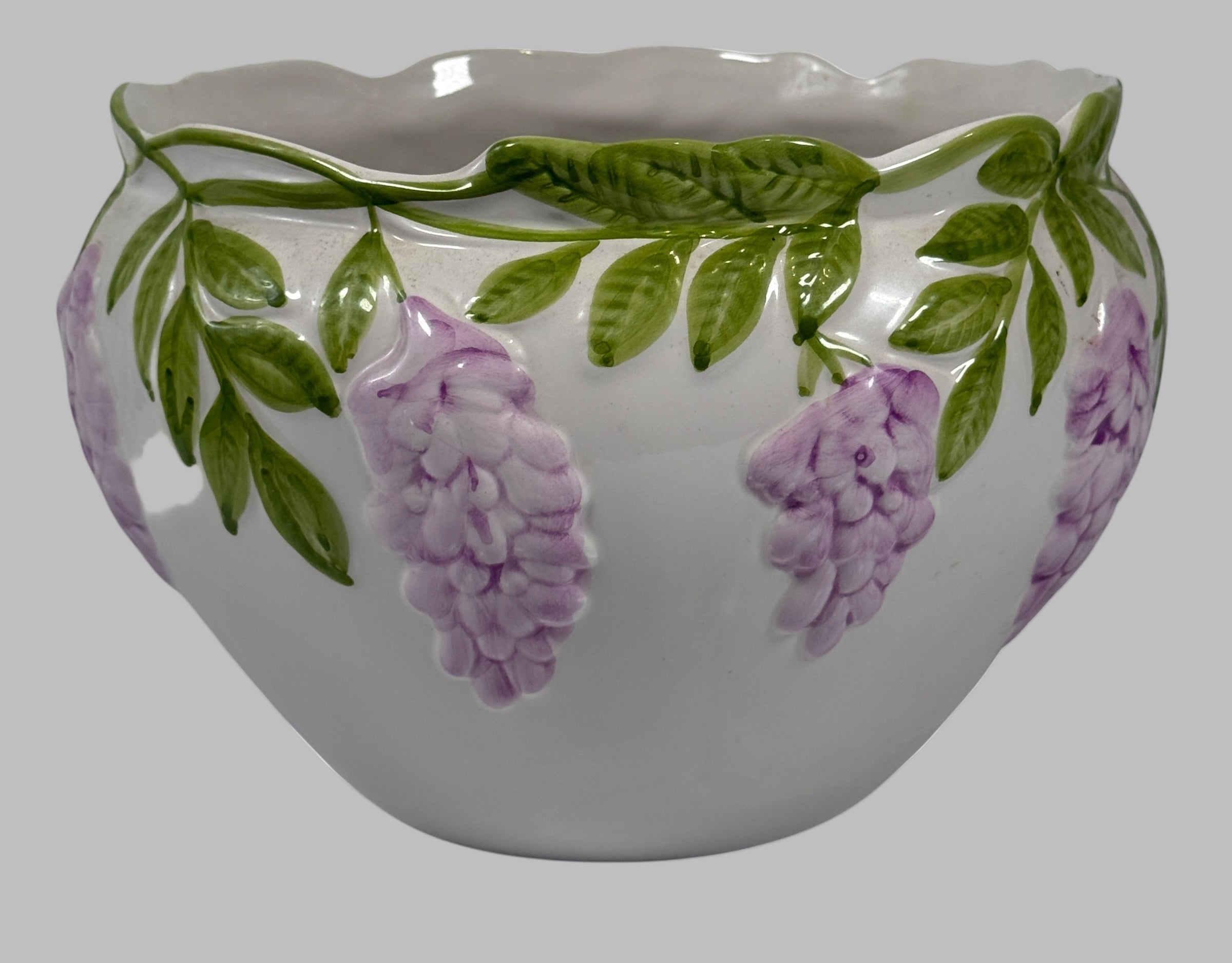 Ceramic pot with floral design featuring purple flowers and green leaves on a white background