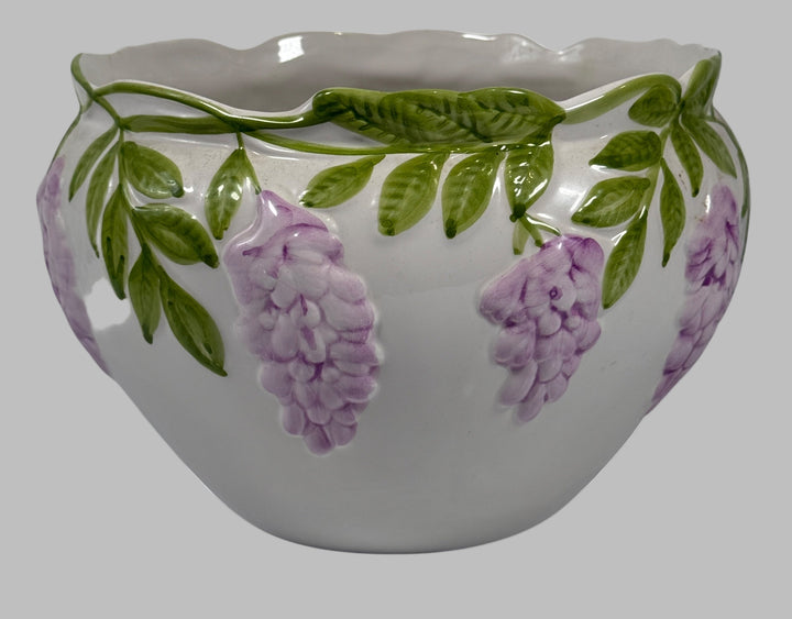Ceramic pot with floral design featuring purple flowers and green leaves on a white background