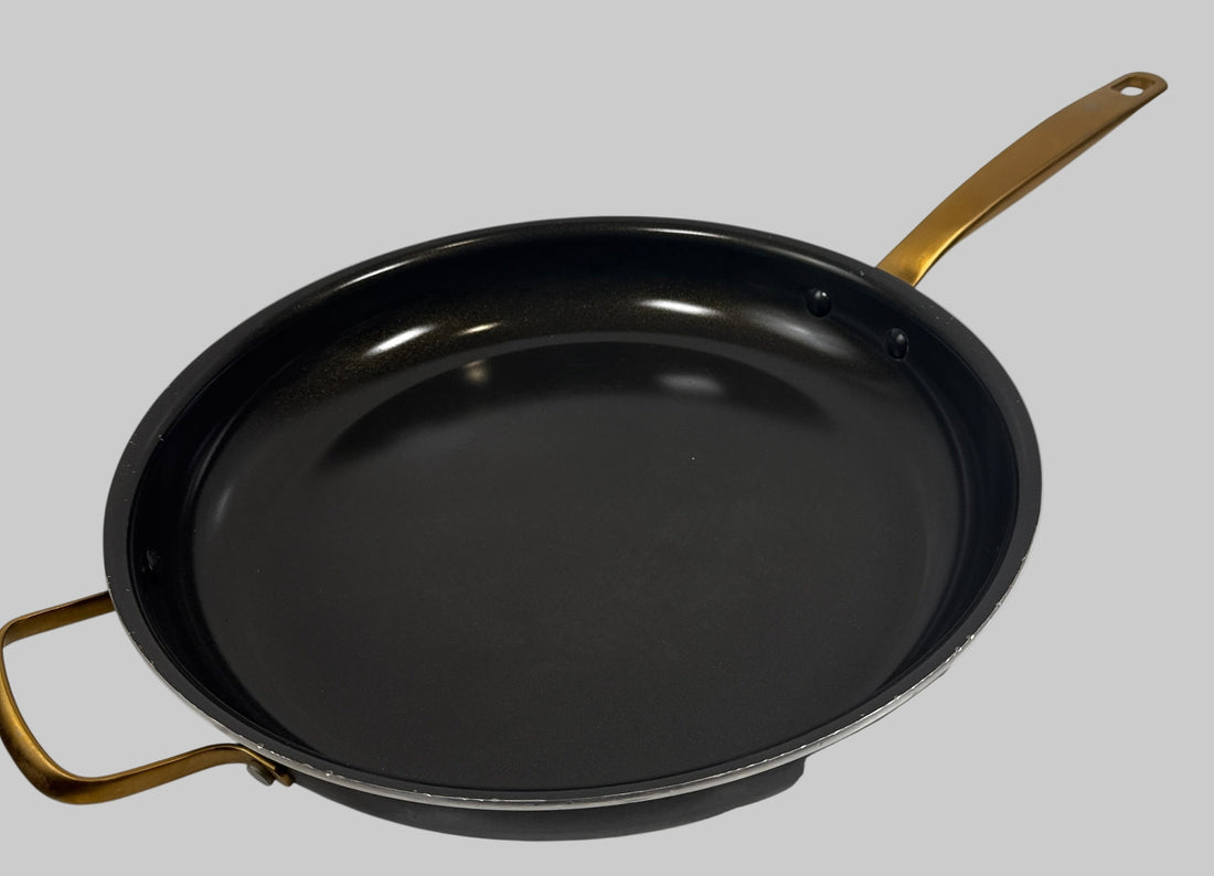 Black frying pan with gold handles on a white background