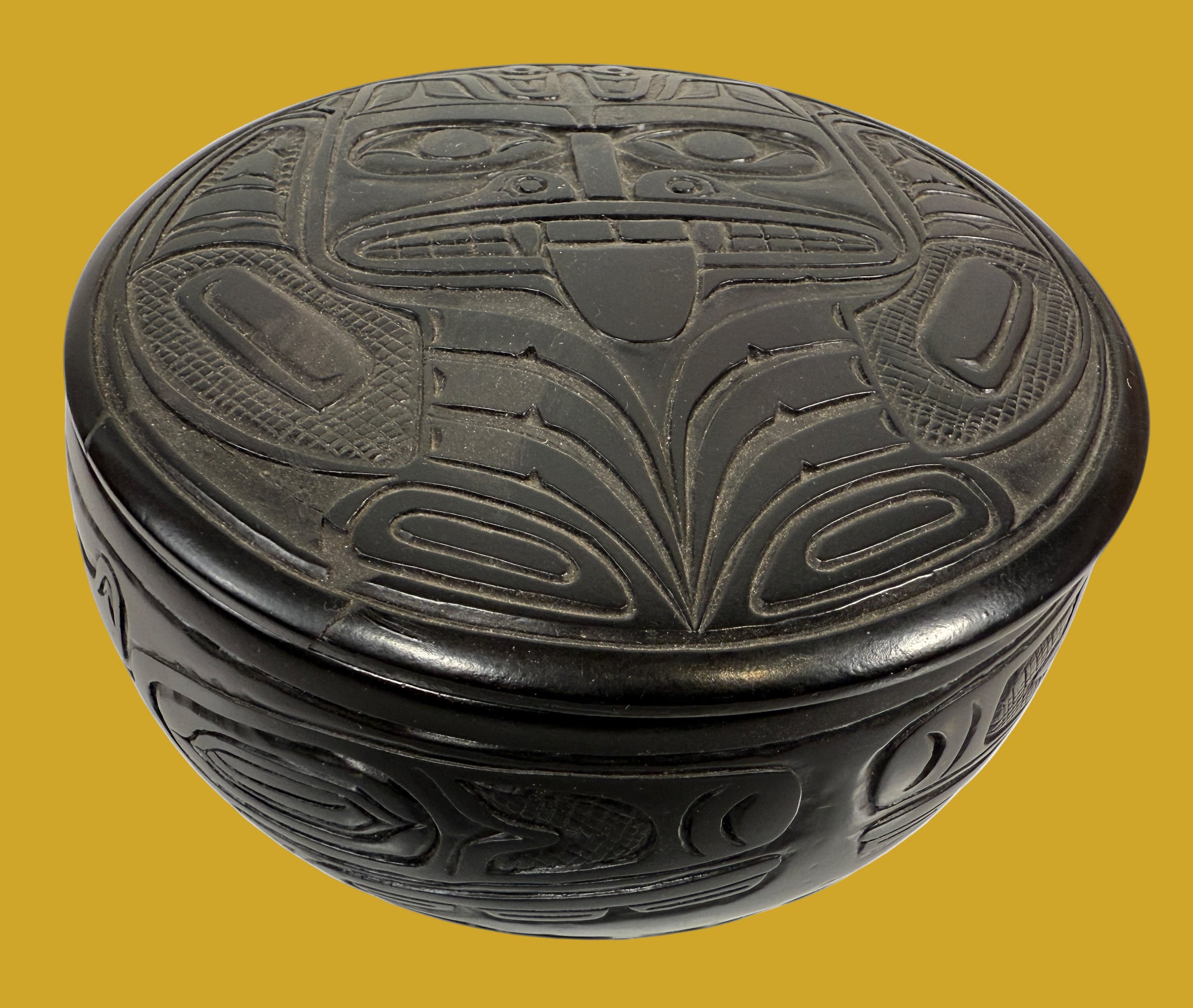 Decorative black box with intricate carvings on a yellow background