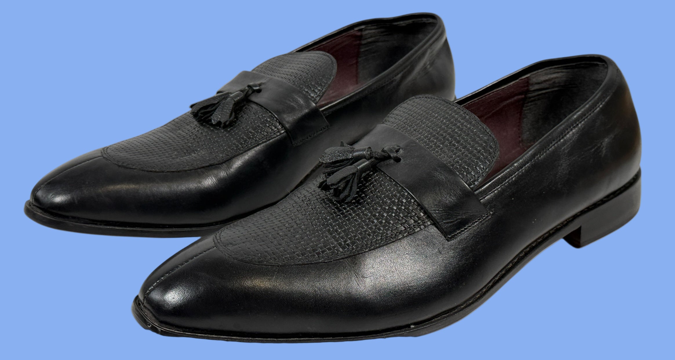 Pair of black leather loafers with tassels on a white background