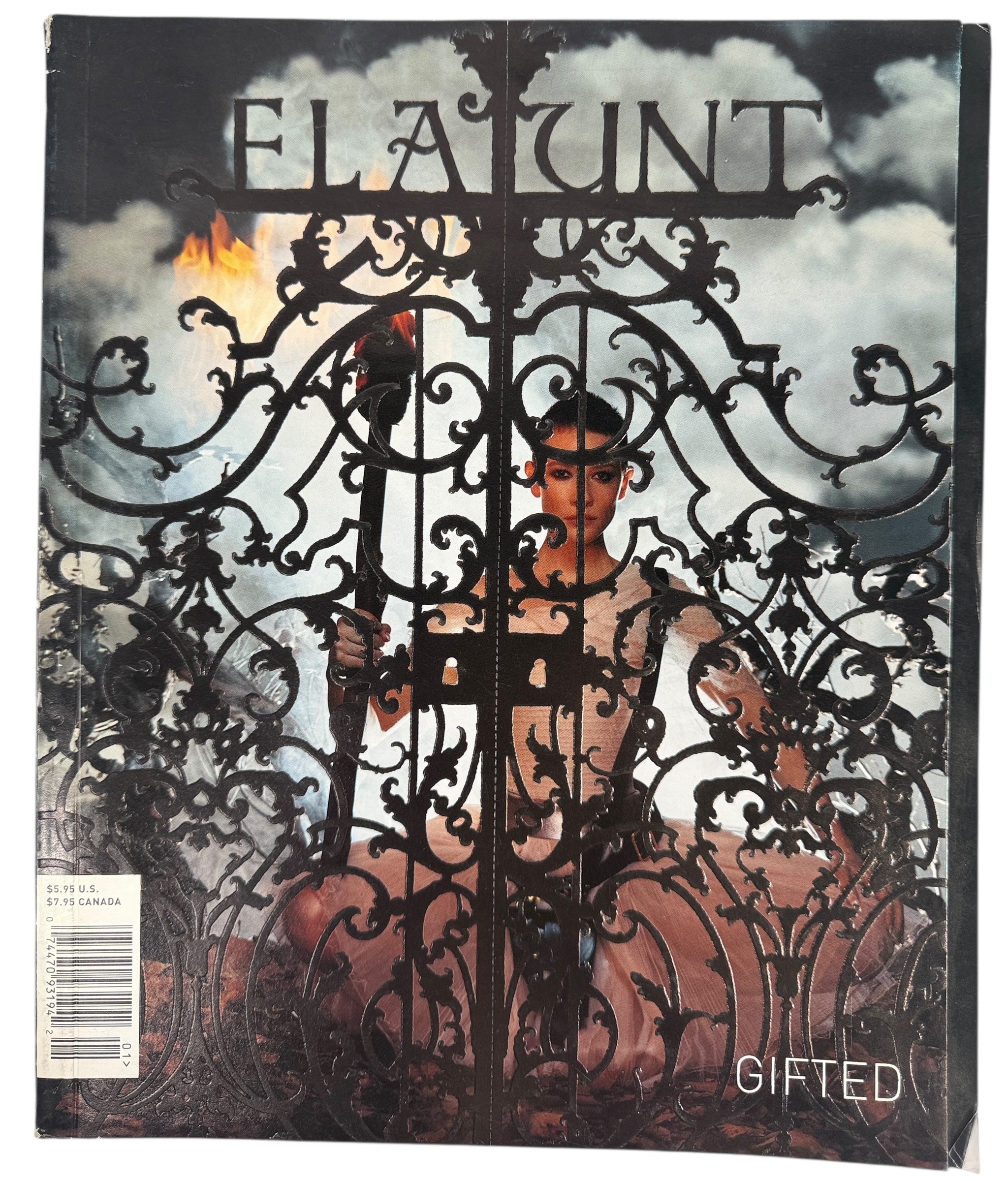 Magazine cover with a person behind an ornate gate, featuring the brand Flaunt. Gifted