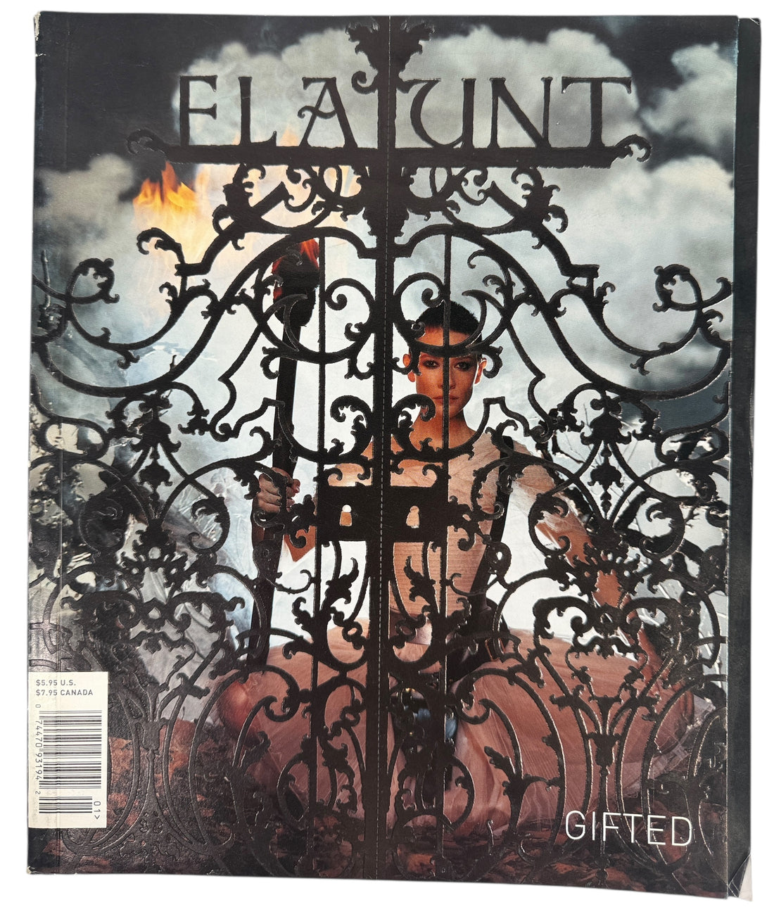 Magazine cover with a person behind an ornate gate, featuring the brand Flaunt. Gifted