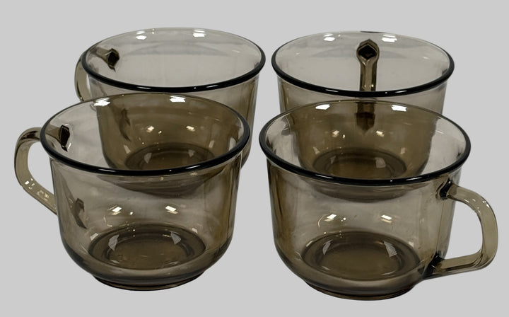Set of four smoked glass mugs with handles on a white background
