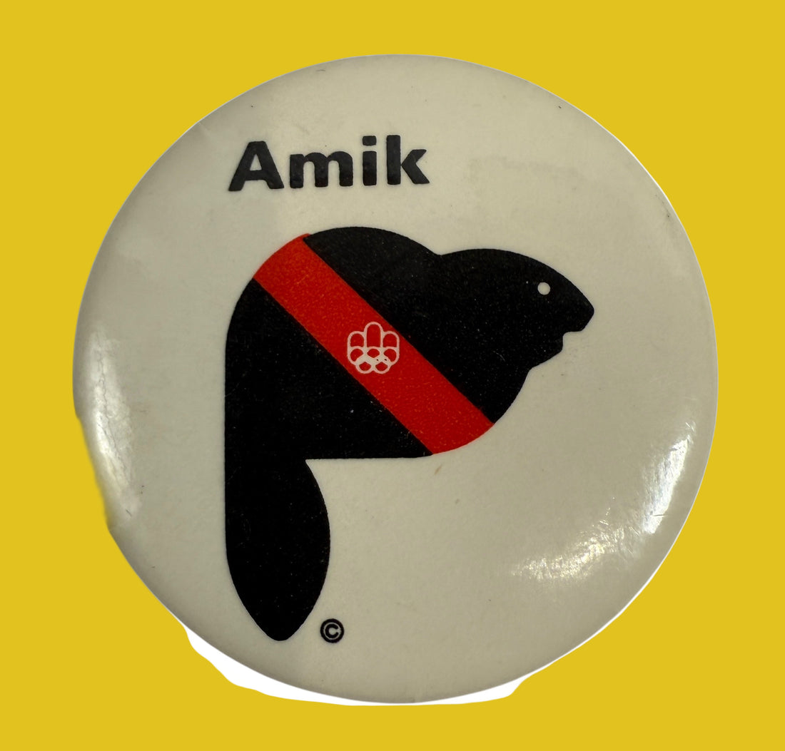 Button badge with a black silhouette of a beaver, red stripe, and 'Amik' text on a beige background
