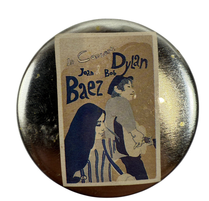 Button badge with illustration of Joan Baez and Bob Dylan on a reflective surface