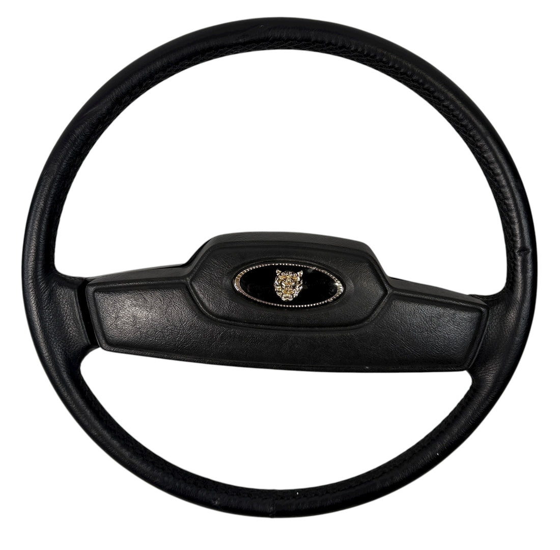 OEM Jaguar XJ6 Series III steering wheel with horn pad. Genuine 1980–87 UK-made replacement part in good driver condition. Vintage Jaguar interior collectible.
