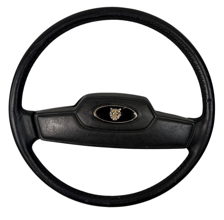 OEM Jaguar XJ6 Series III steering wheel with horn pad. Genuine 1980–87 UK-made replacement part in good driver condition. Vintage Jaguar interior collectible.
