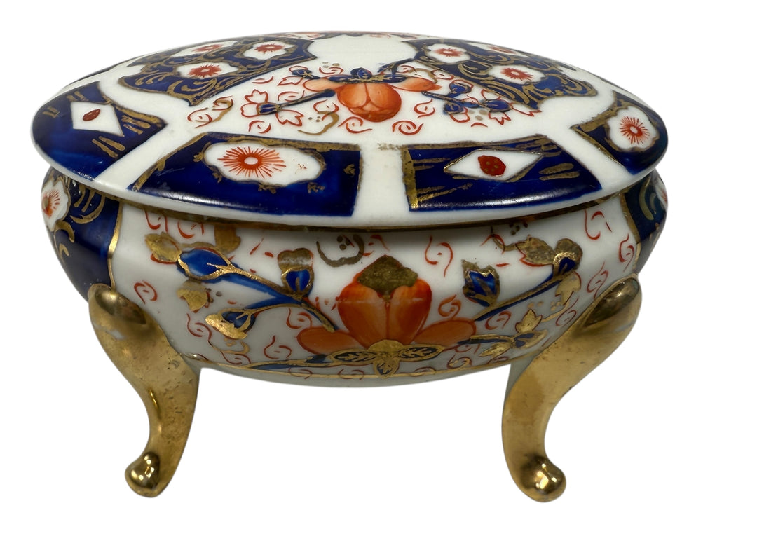 Japanese Imari style porcelain trinket box with lid and brass feet. Decorative vintage export ware in cobalt blue, red, and gilt accents.