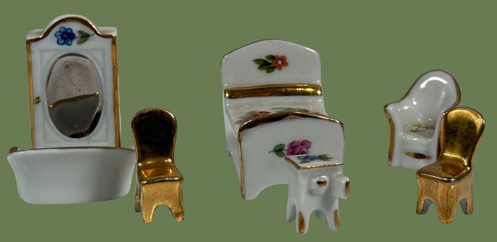 Set of miniature dollhouse furniture including a sink, chairs, and table on a white background