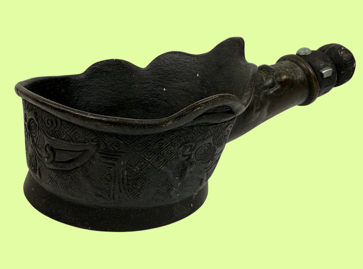 Decorative black metal object with intricate designs on a white background