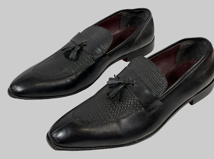 Pair of black leather loafers with tassels on a white background