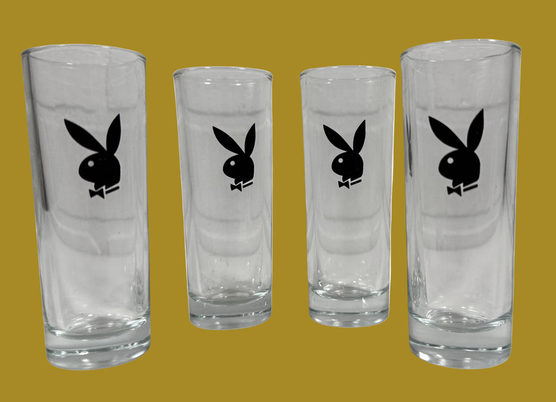 Four clear glasses with Playboy Bunny logo on a white background