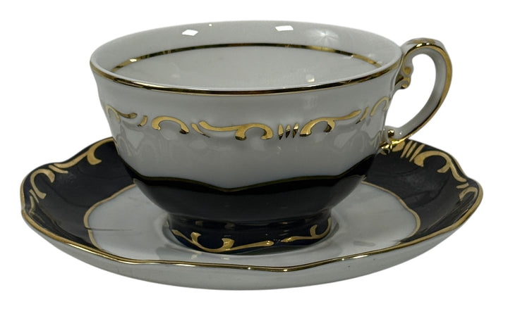 White teacup with gold accents on a matching saucer with black border