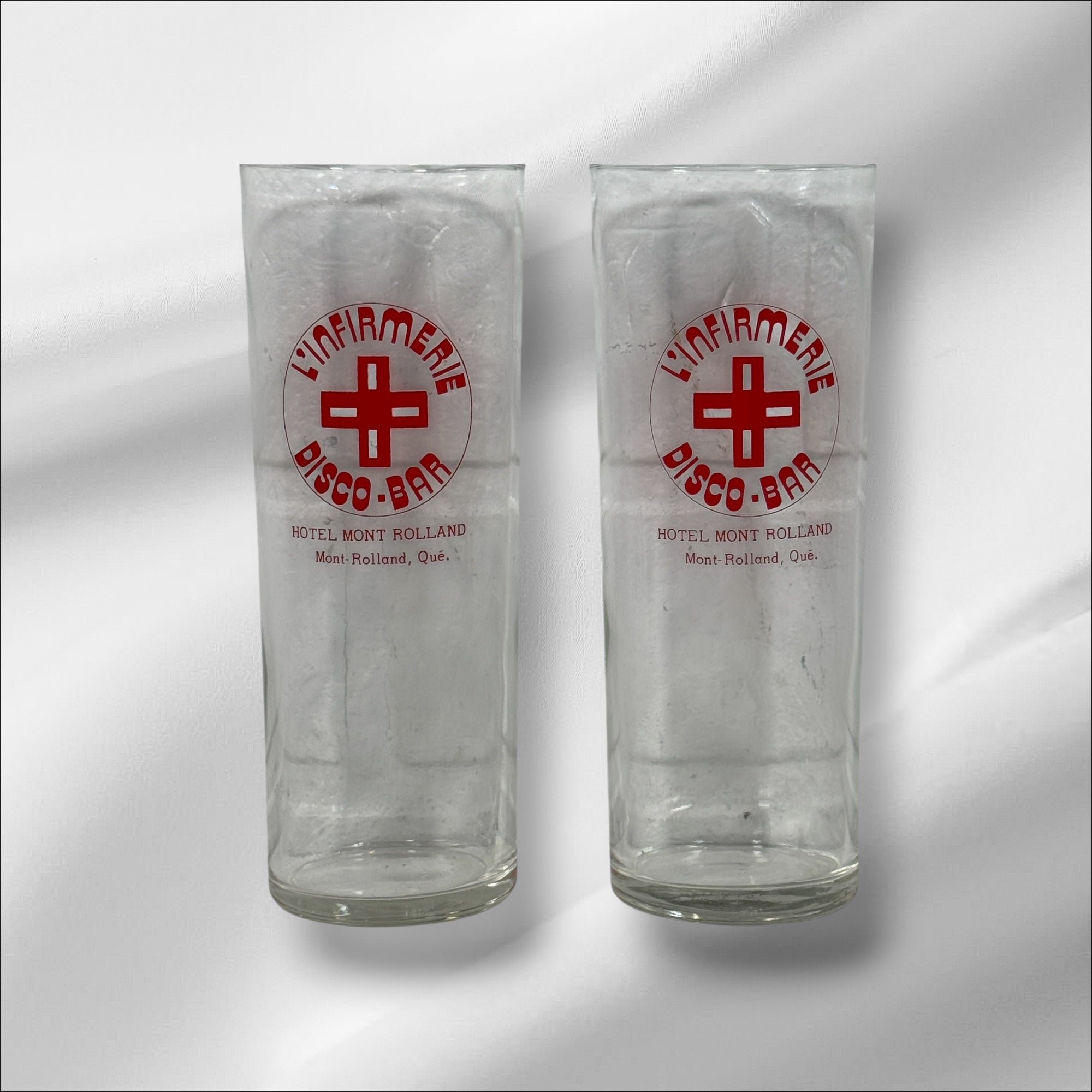 Vintage L’Infirmerie Disco-Bar souvenir glasses from Mont-Rolland, Québec. Rare nightlife memorabilia in excellent condition. Pair of original high-ball glasses.