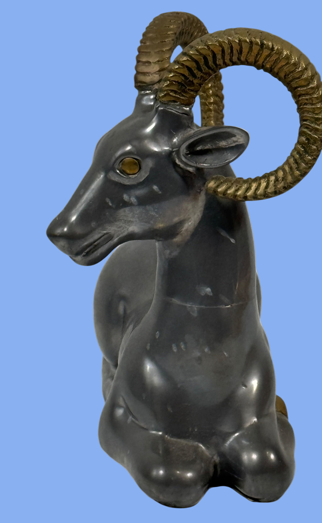 Decorative ram sculpture with gold horns on a white background