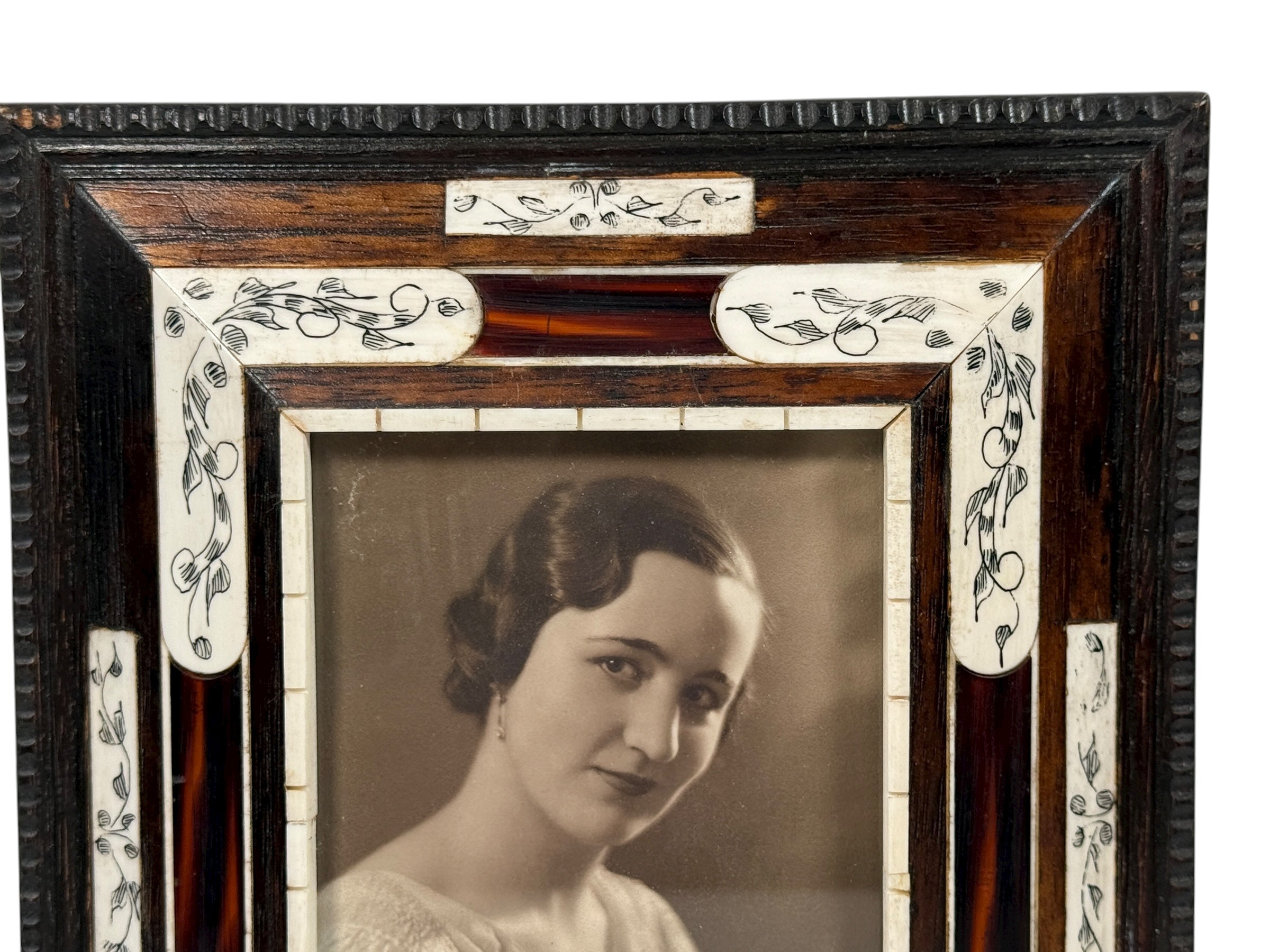 Vintage portrait of a woman in an ornate wooden frame with decorative elements.
