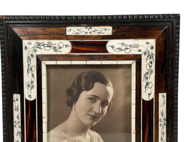 Vintage portrait of a woman in an ornate wooden frame with decorative elements.