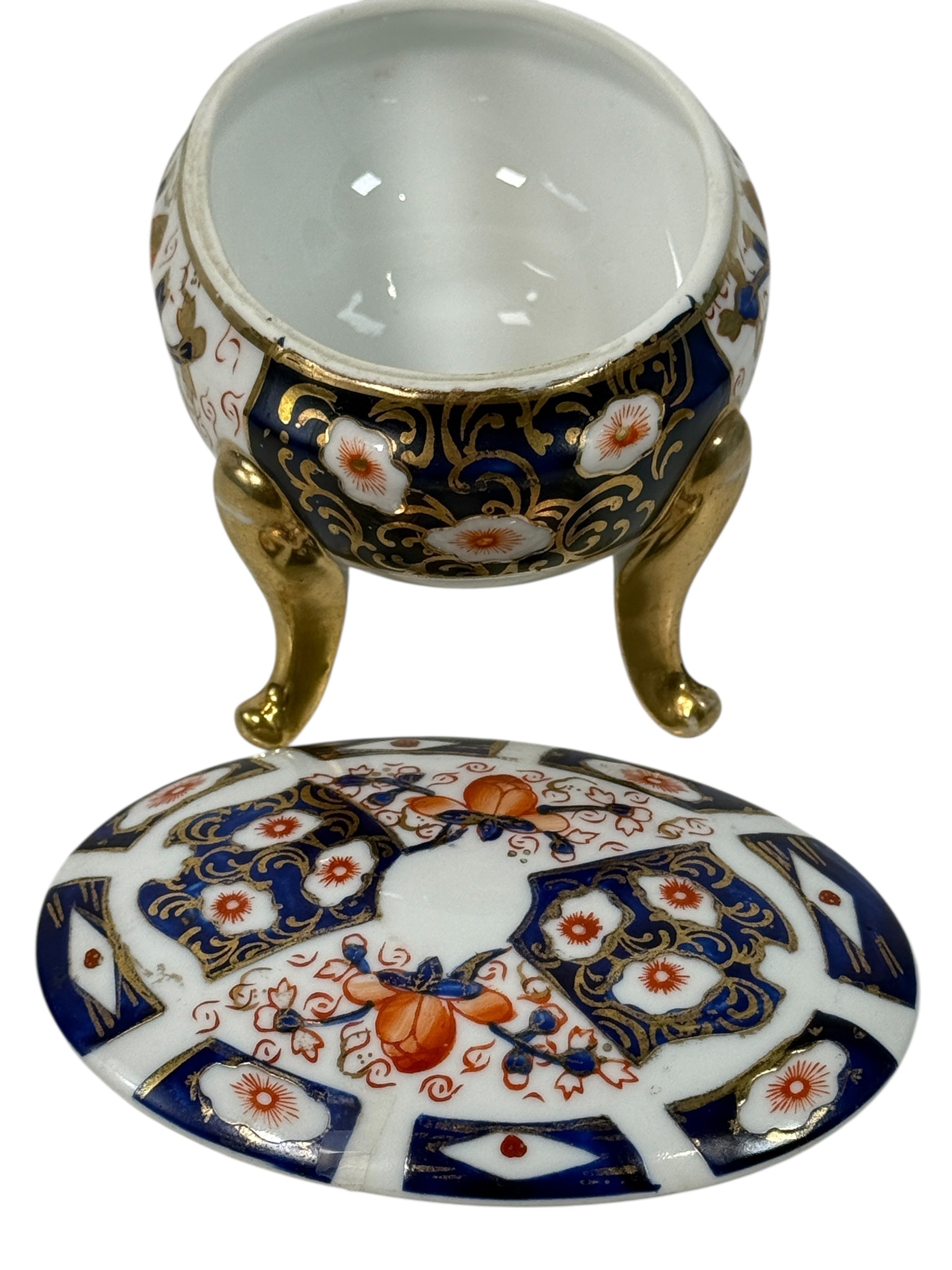 Japanese Imari style porcelain trinket box with lid and brass feet. Decorative vintage export ware in cobalt blue, red, and gilt accents.
