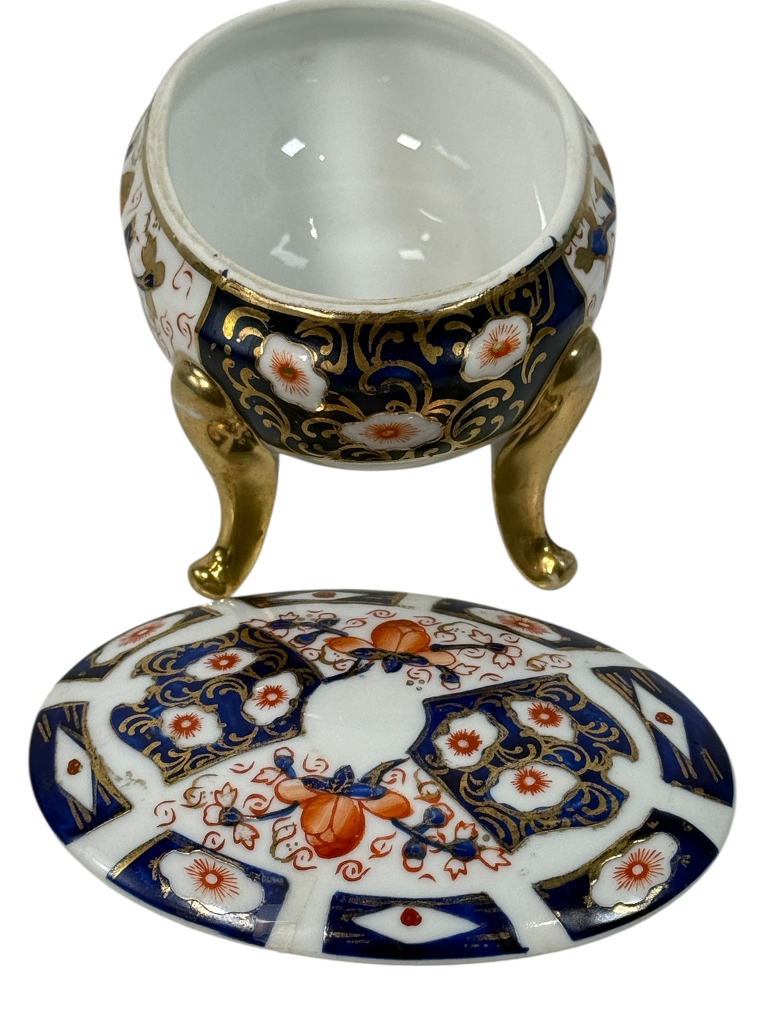 Japanese Imari style porcelain trinket box with lid and brass feet. Decorative vintage export ware in cobalt blue, red, and gilt accents.