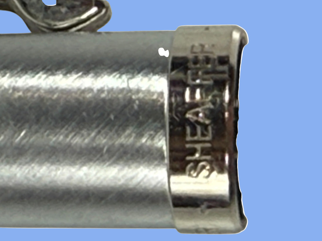 Close-up of a silver hair clip with 'Sheaffer' branding on a white background