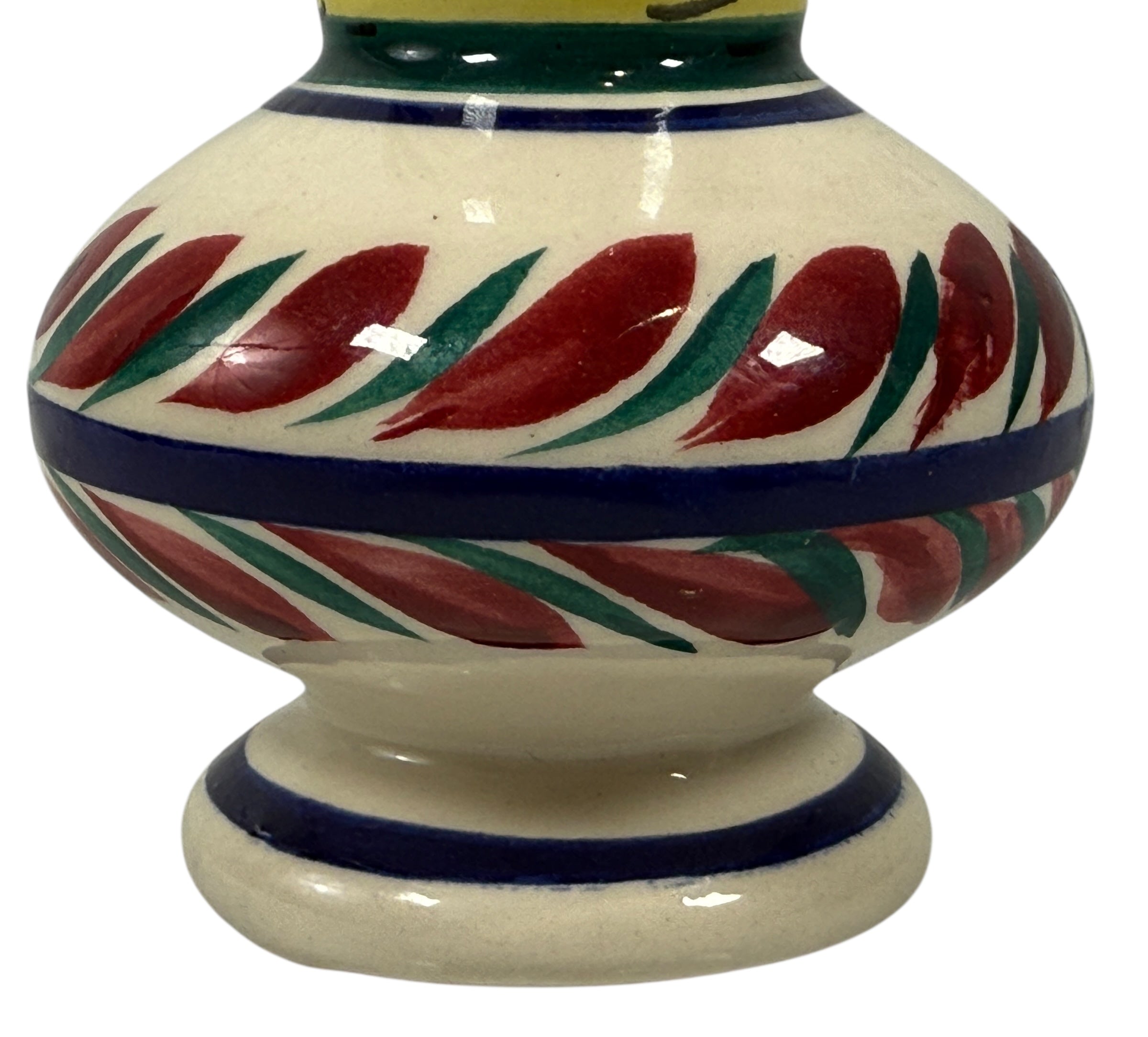 Ceramic vase with red and green leaf patterns on a white background