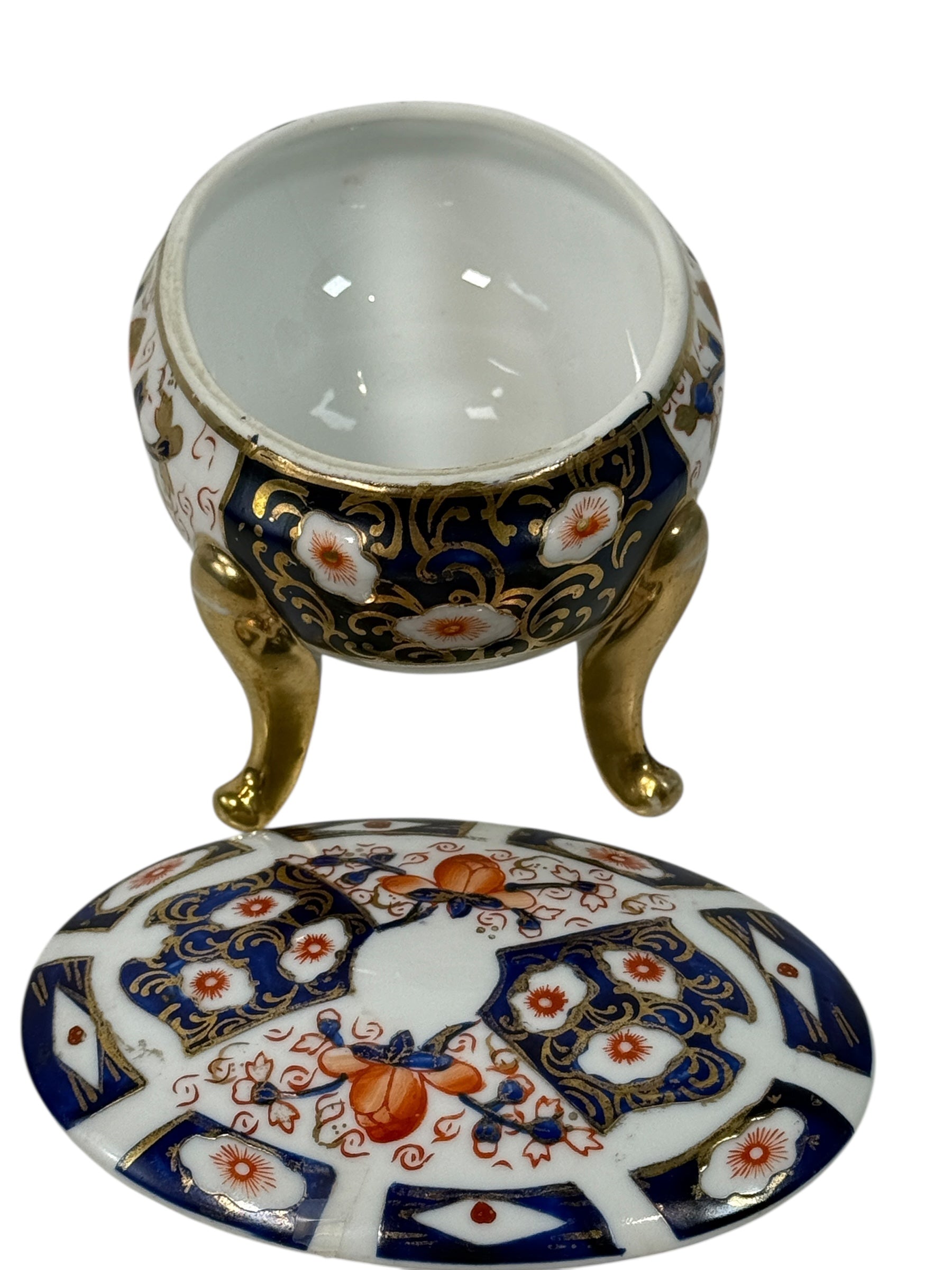 Japanese Imari style porcelain trinket box with lid and brass feet. Decorative vintage export ware in cobalt blue, red, and gilt accents.