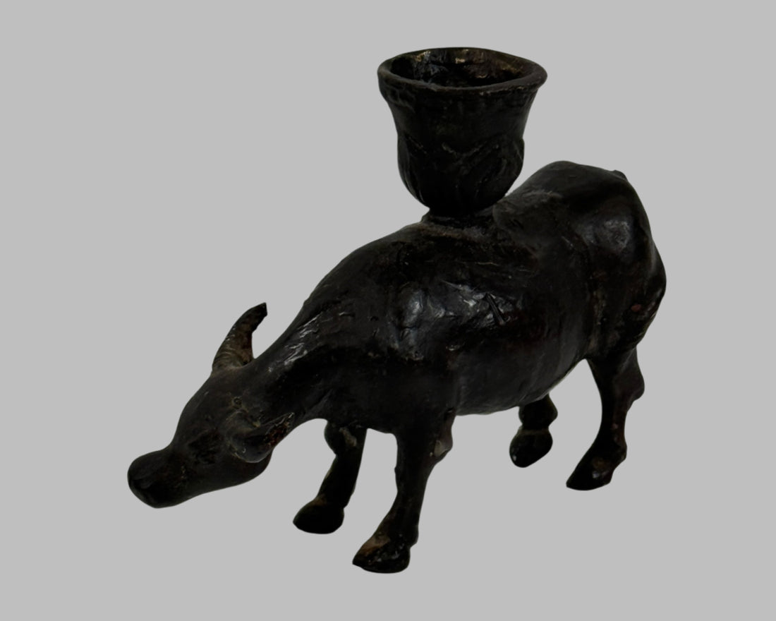 Black metal bull-shaped candle holder on a white background