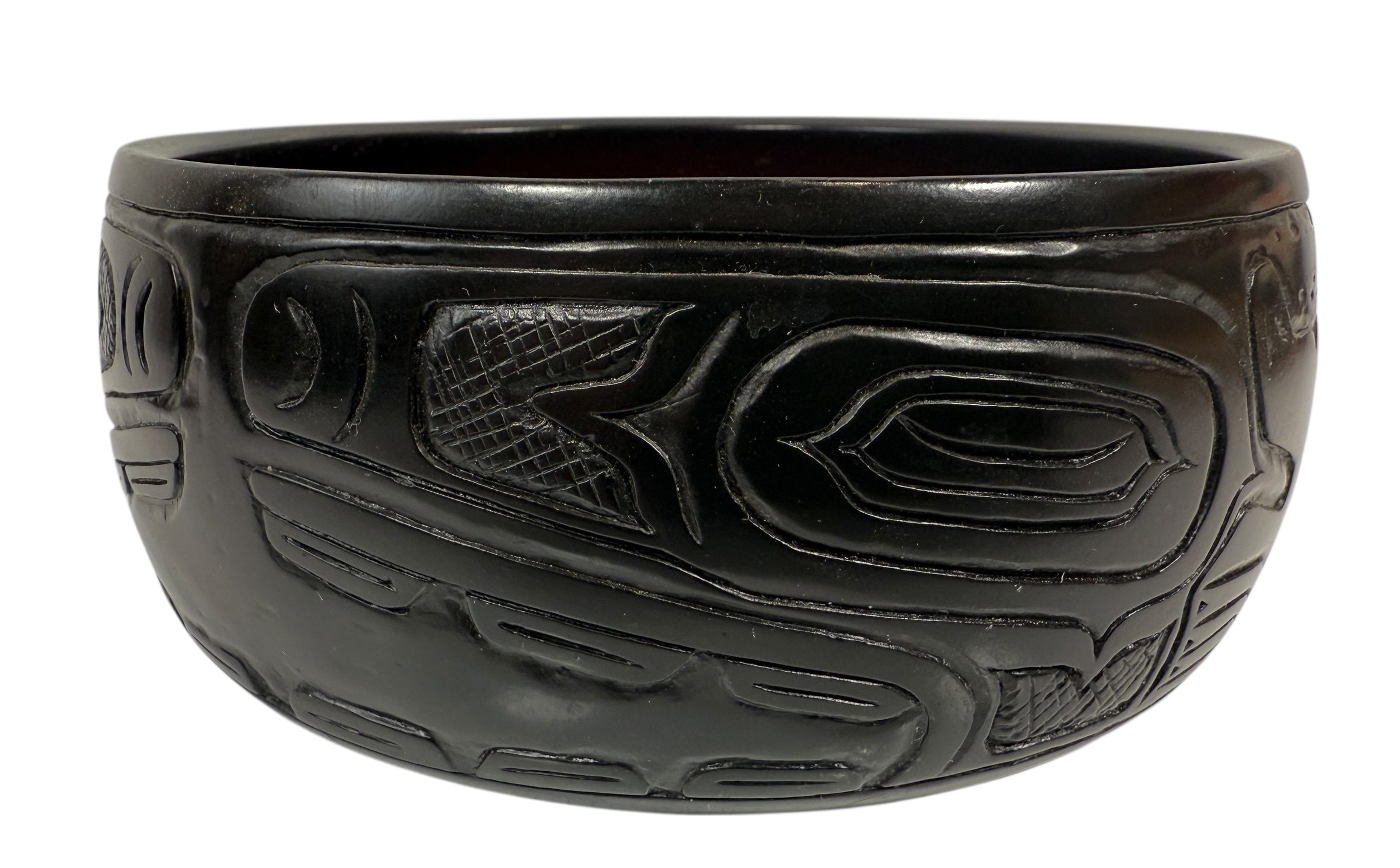 Black ceramic bowl with intricate carvings on a white background