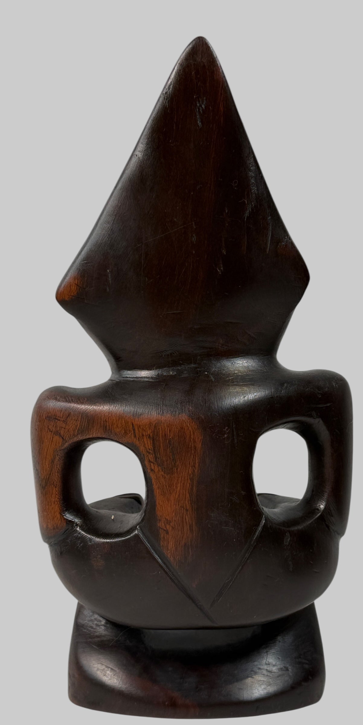 Wooden sculpture with a pointed top and circular base on a white background