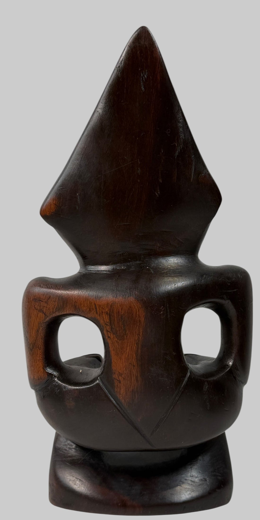 Wooden sculpture with a pointed top and circular base on a white background