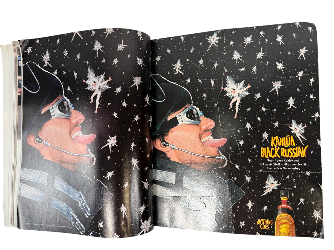 Open book with a black and white illustration of a person wearing sunglasses and a hat, with fairy graphics on a starry background. Kahláu Black Russian branding is visible.