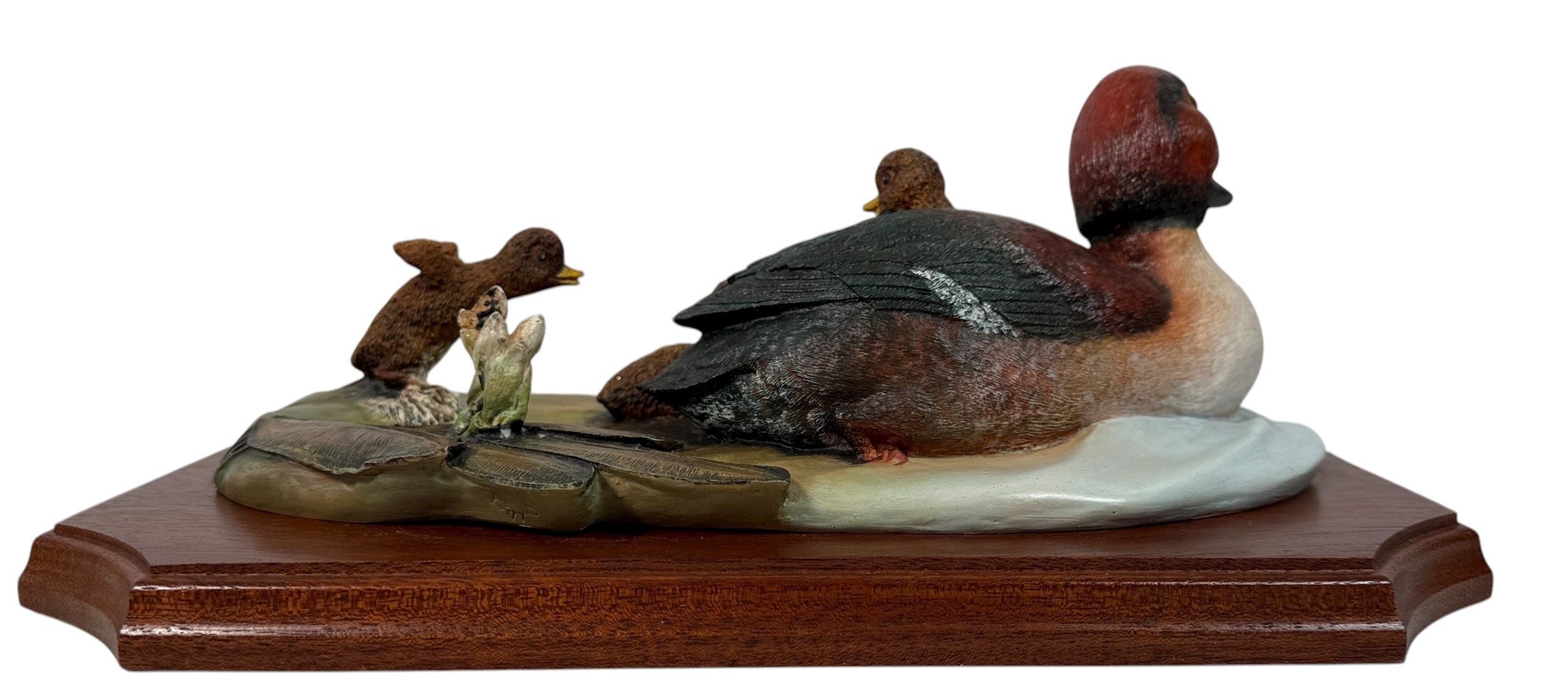 Decorative figurine of two ducks on a rock with a small dog, on a wooden base.