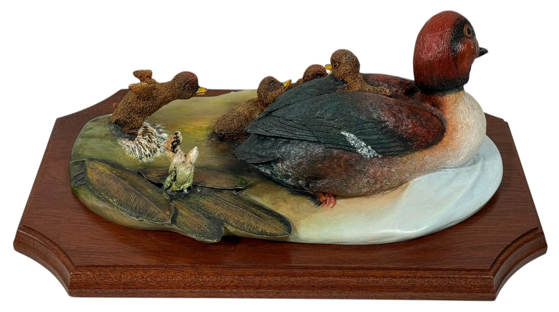 Decorative duck sculpture on a wooden base with a white background