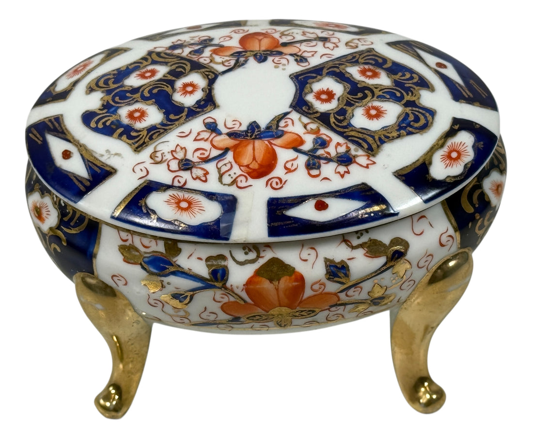 Japanese Imari style porcelain trinket box with lid and brass feet. Decorative vintage export ware in cobalt blue, red, and gilt accents.