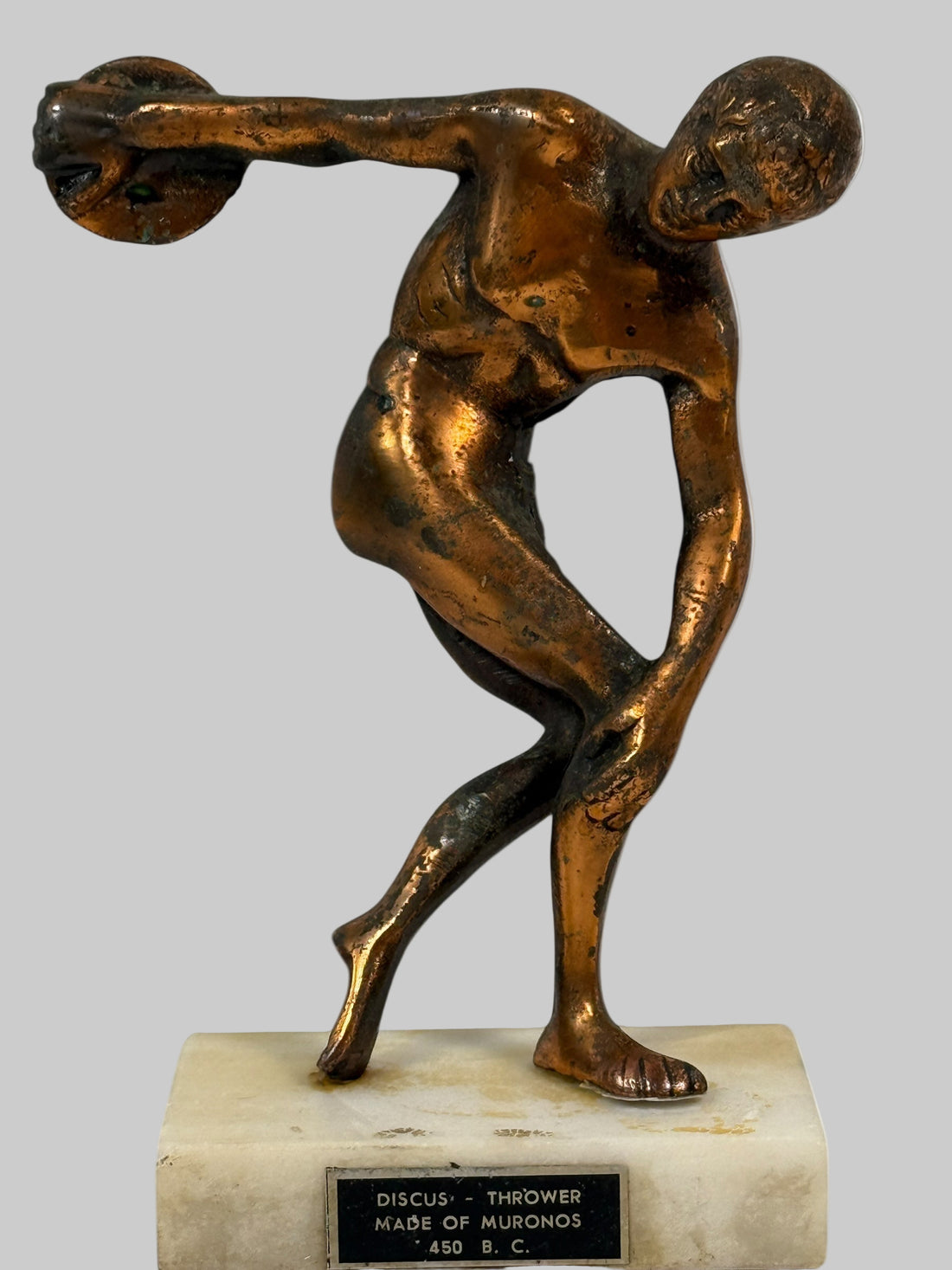 Bronze statue of a discus thrower on a white background
