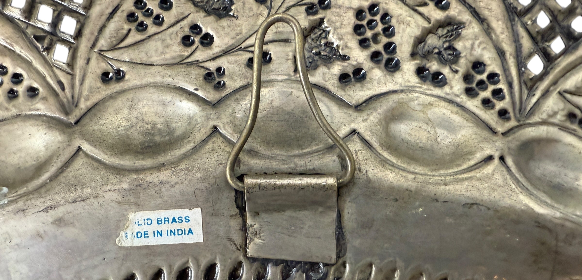Decorative metal object with intricate patterns and a visible 'Made in India' label.
