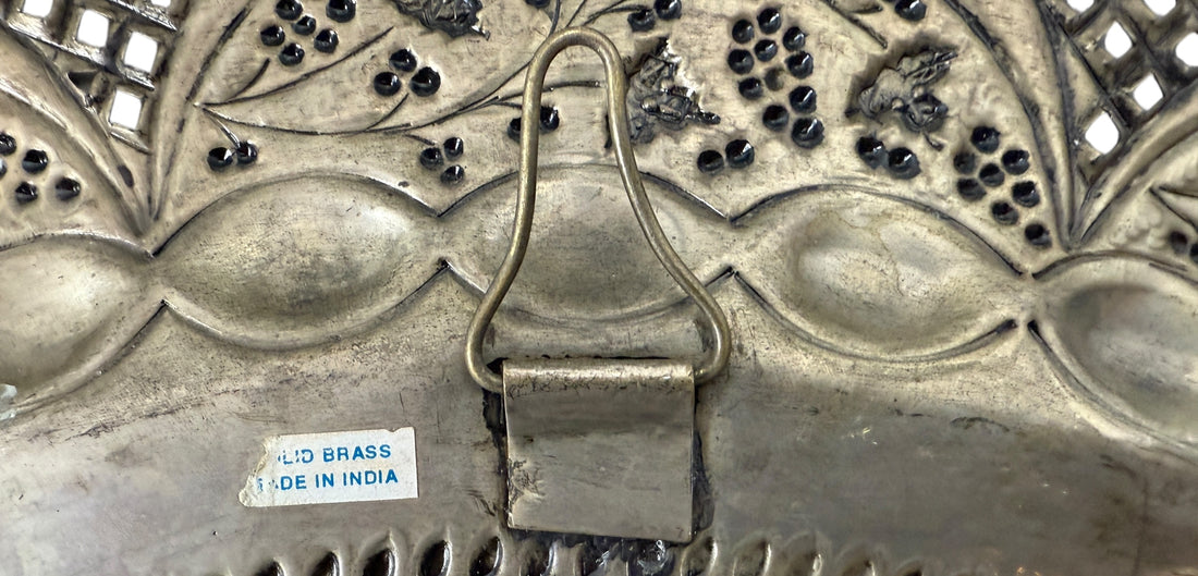 Decorative metal object with intricate patterns and a visible 'Made in India' label.