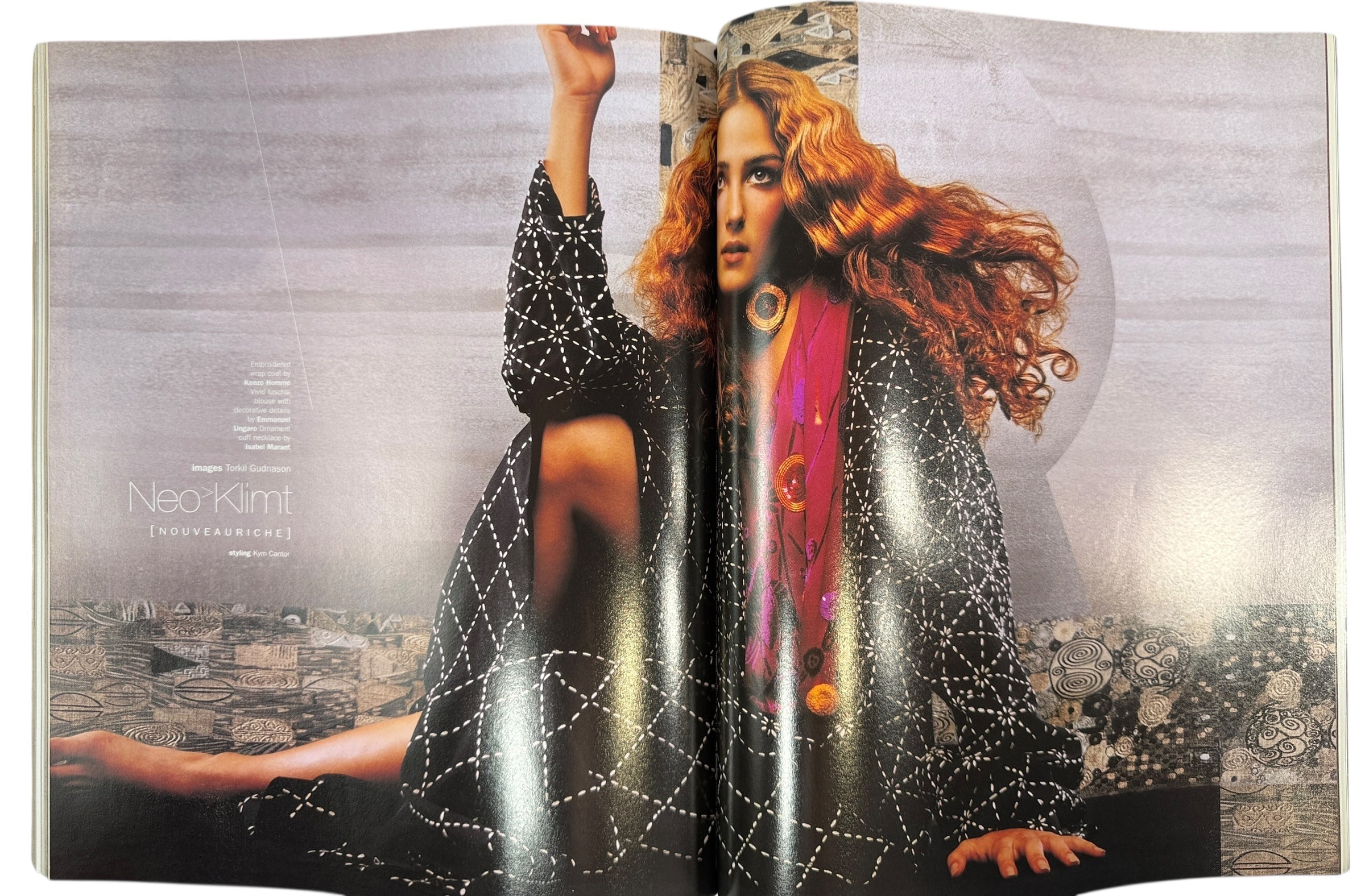 Open magazine or book with a model wearing a black outfit with white patterns on a cityscape background