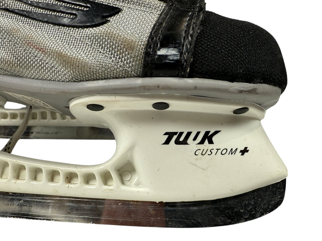 Close-up of a ice skate with 'Tuuk Custom' branding on a white background