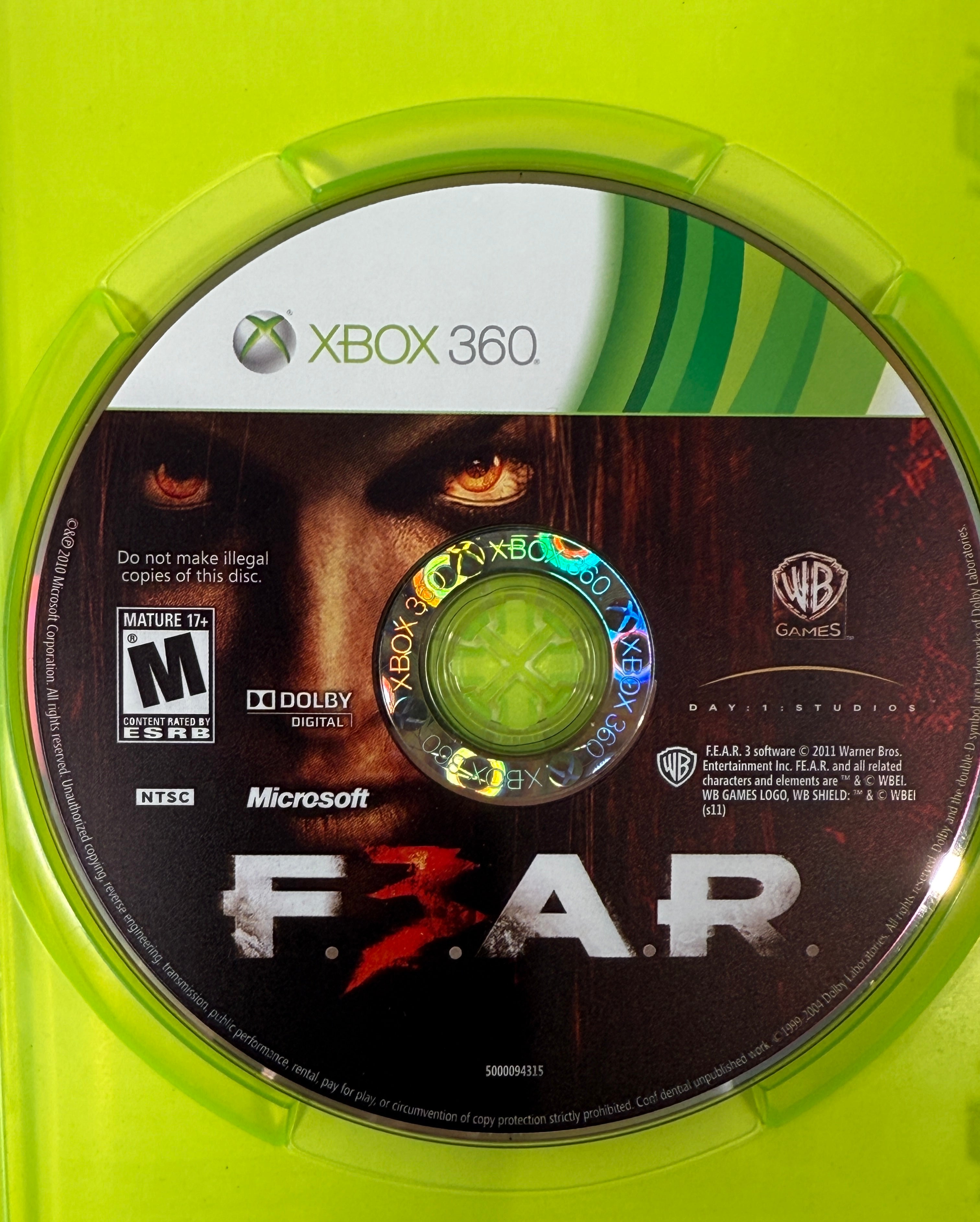Xbox 360 game disc with 'F.E.A.R.' branding on a green background