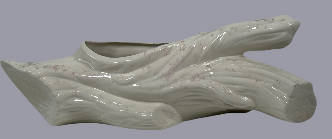 White ceramic planter shaped like a wave on a gray background