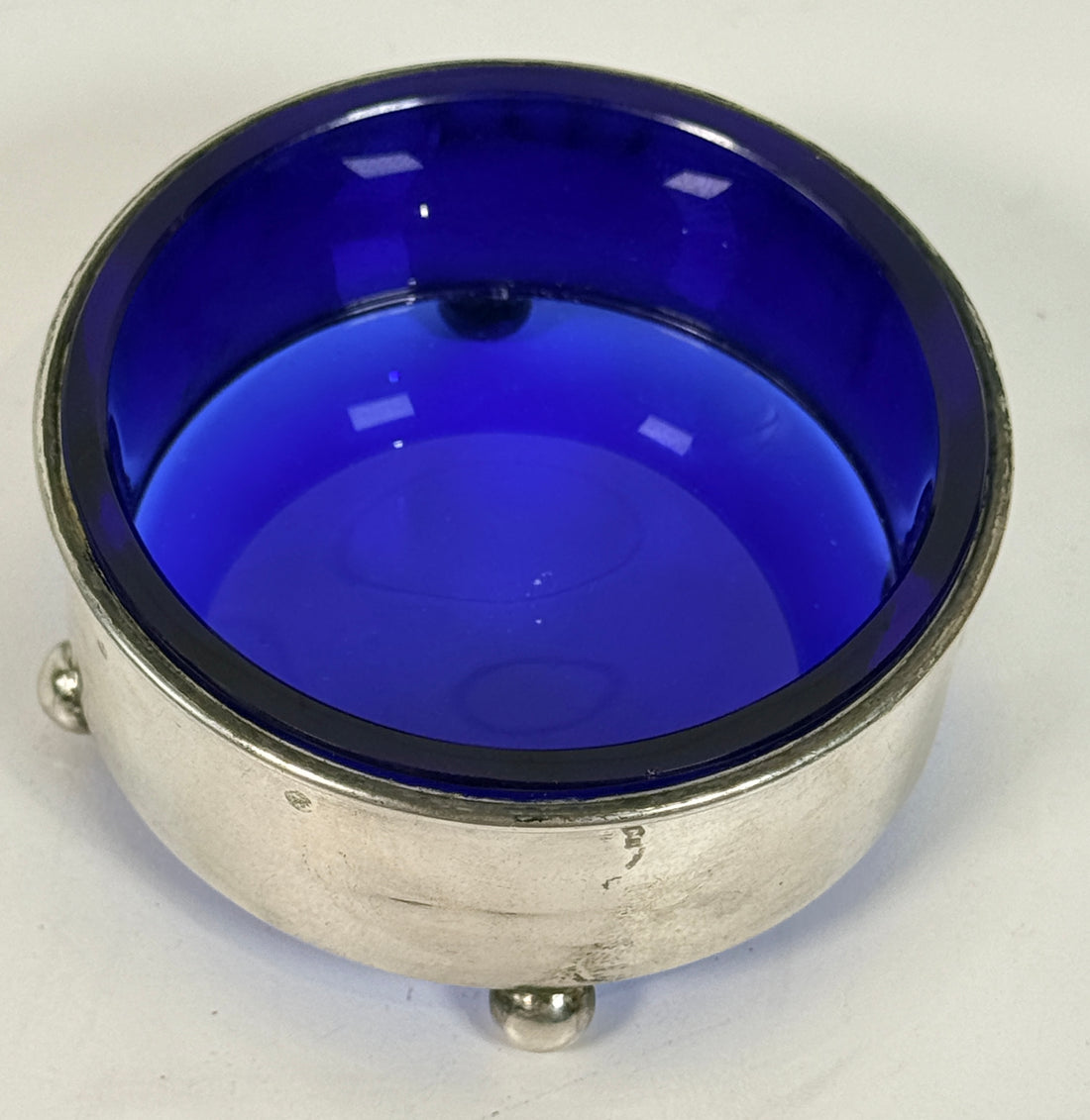 Vintage sterling silver coaster with cobalt blue glass insert, marked sterling 9886. Elegant barware or decorative dish with classic three-foot design.