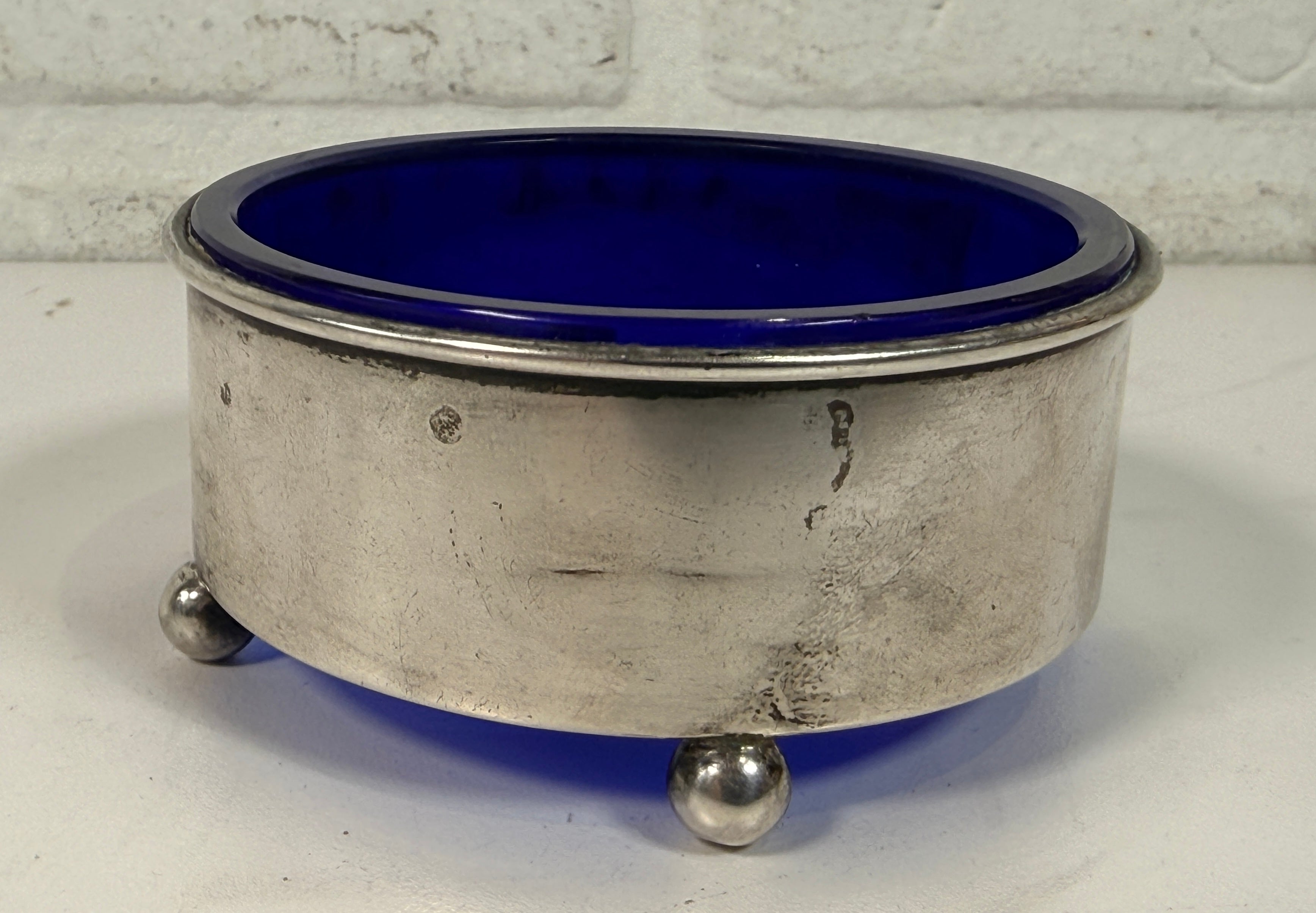 Vintage sterling silver coaster with cobalt blue glass insert, marked sterling 9886. Elegant barware or decorative dish with classic three-foot design.