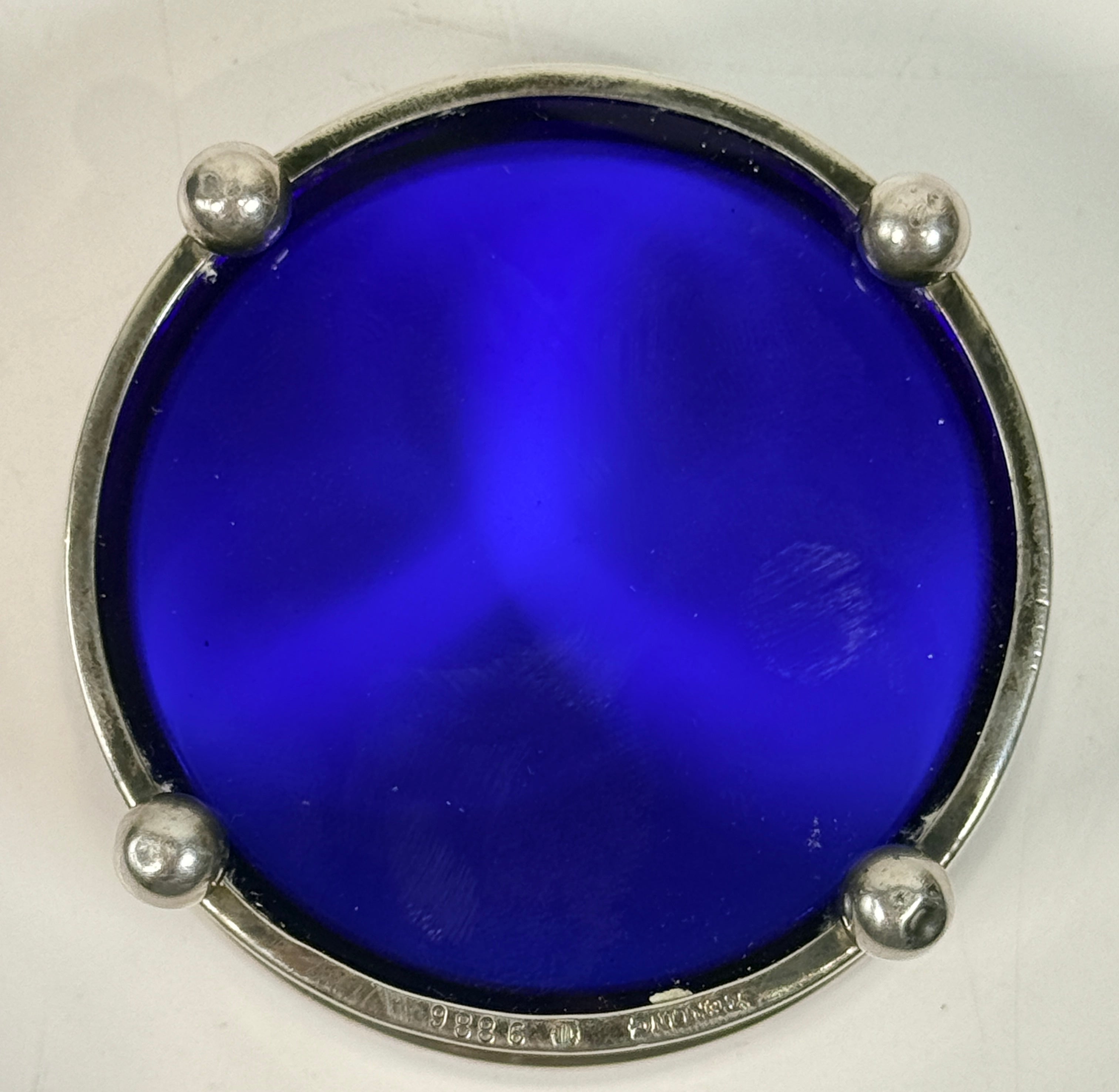Vintage sterling silver coaster with cobalt blue glass insert, marked sterling 9886. Elegant barware or decorative dish with classic three-foot design.