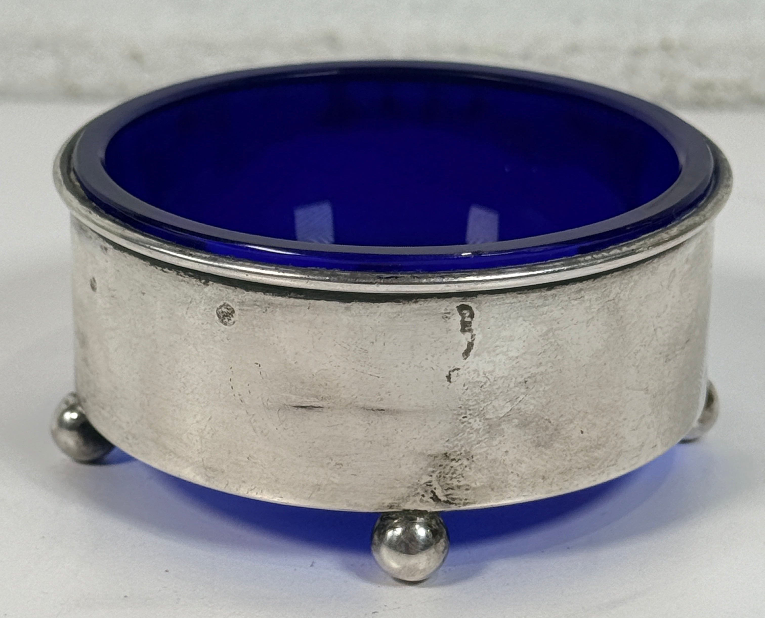 Vintage sterling silver coaster with cobalt blue glass insert, marked sterling 9886. Elegant barware or decorative dish with classic three-foot design.