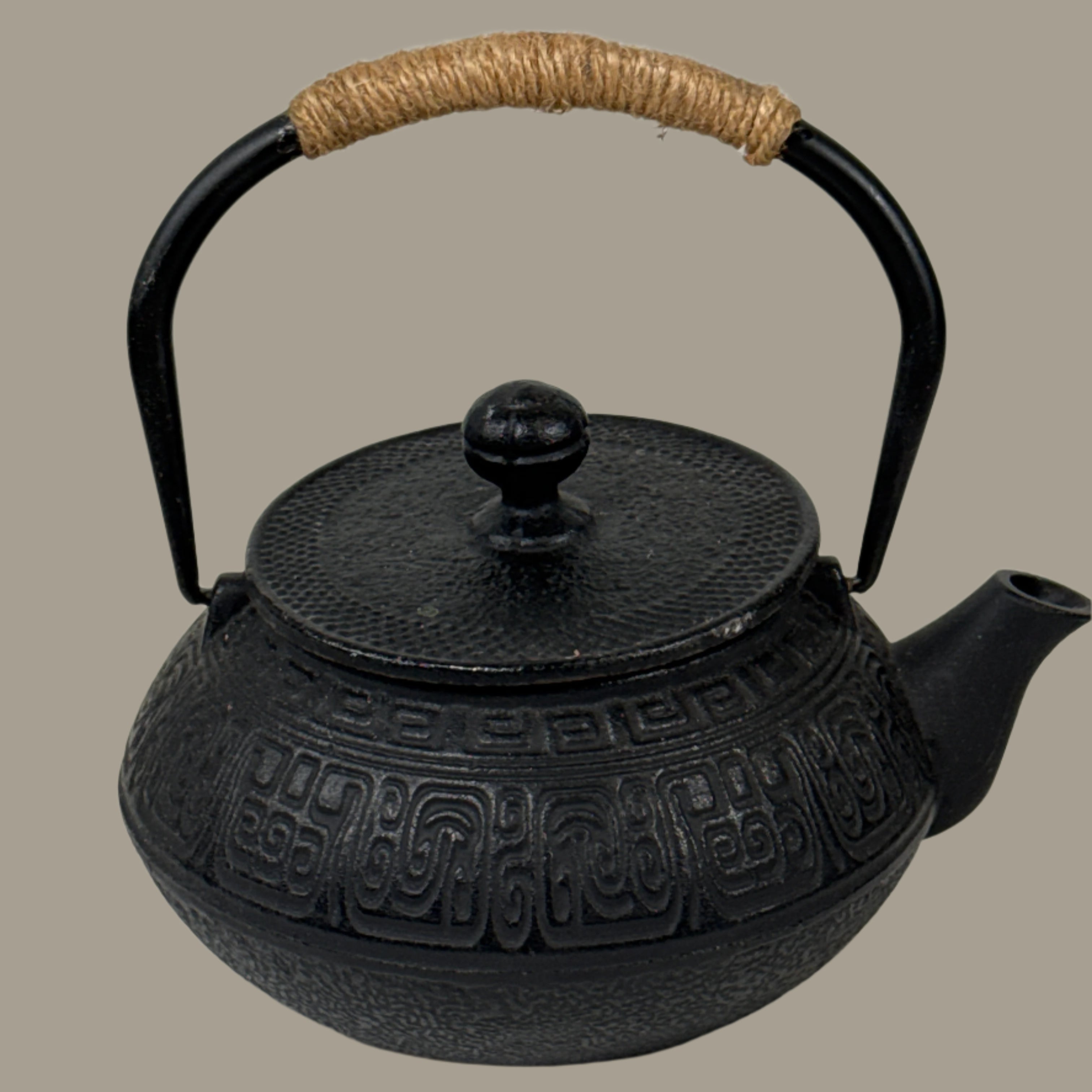Black teapot with a textured design on a white brick wall background